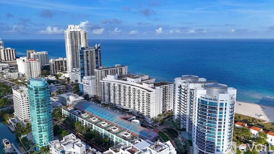 A cityscape with tall buildings and a beach in the background.
