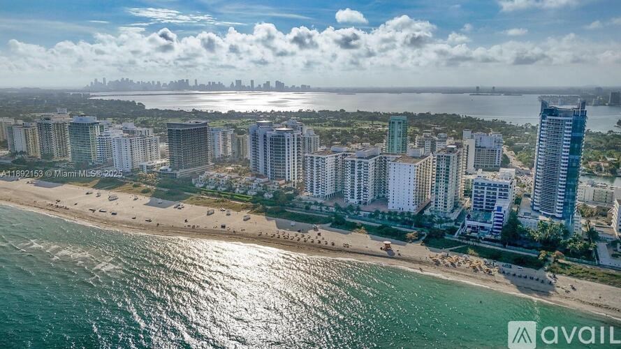 A beachfront cityscape with a clear sky and a body of water in the foreground.