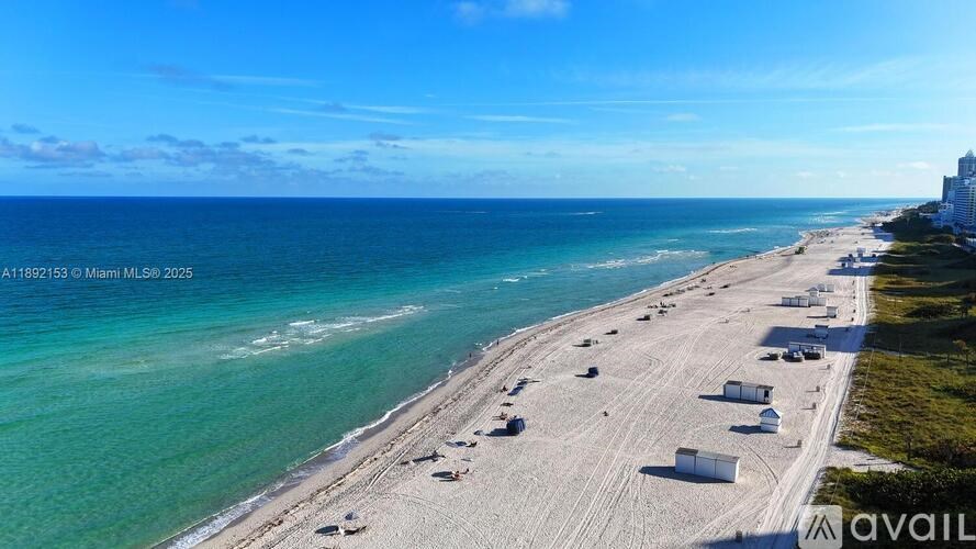 A beach with white sand and buildings on the right side.