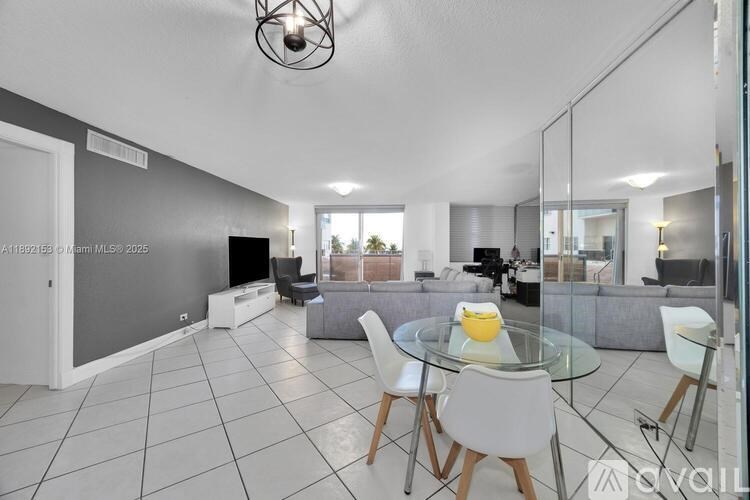 A modern living room with a glass table and white chairs.