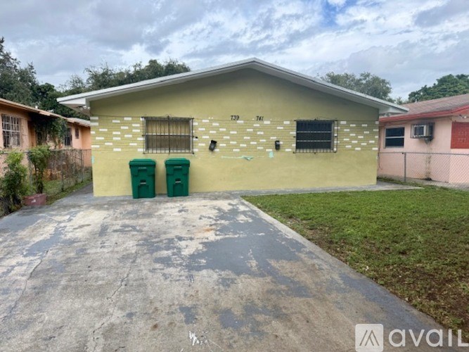 A house with two green bins in front of it.