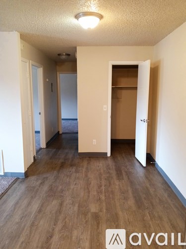 A room with wooden floors and a doorway leading to another room.