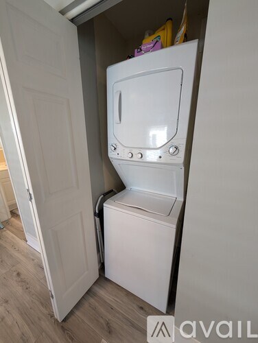 A white washing machine is in a small space under a door.