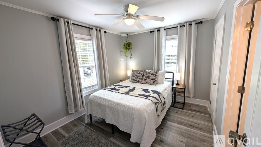 A bedroom with a bed, chair, and ceiling fan.