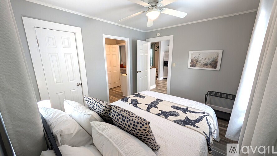 A bedroom with a bed, pillows, and a ceiling fan.