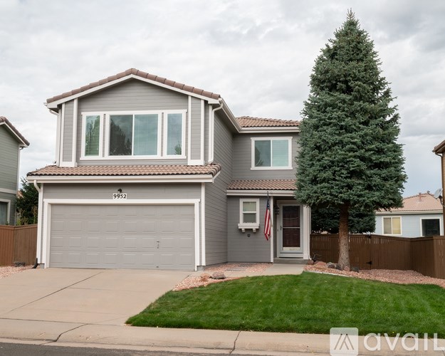 A house with a grey garage door and a tree in front.