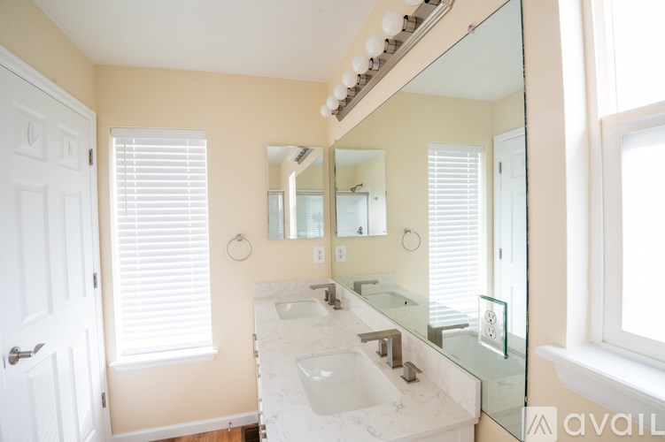 A bathroom with a sink, mirror, and window with blinds.