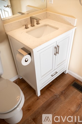 A white bathroom with a toilet, sink, and cabinet.