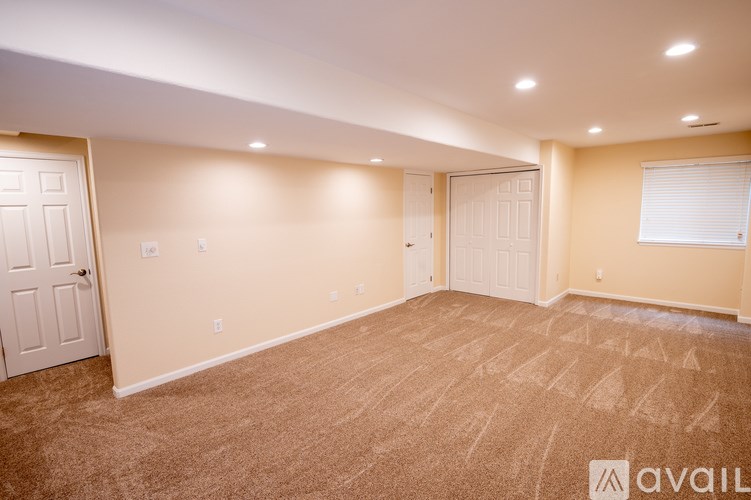 A room with carpeted floor and two doors.
