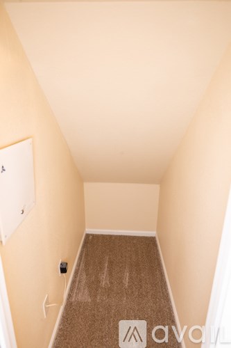 A hallway with a carpeted floor and white walls.
