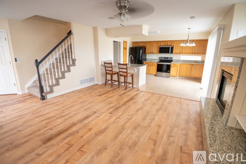 A living room with a staircase and a kitchen in the background.