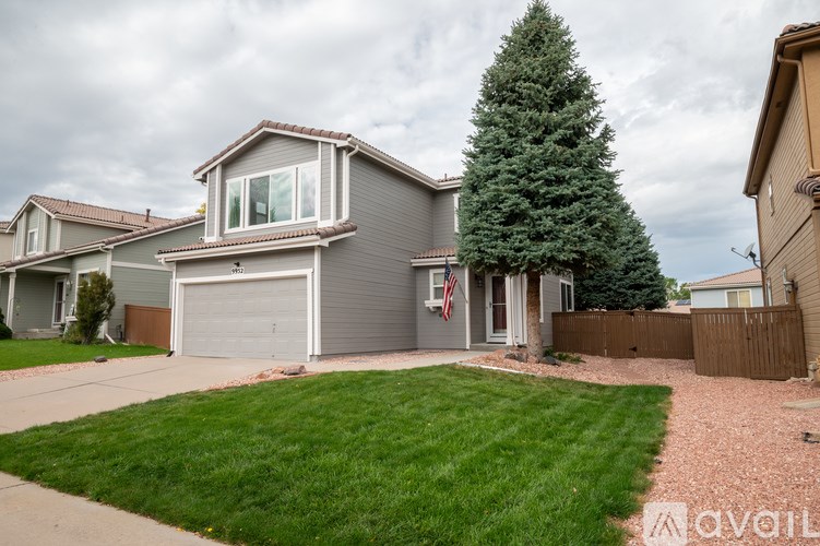 A house with a grey garage door and a tree in front.