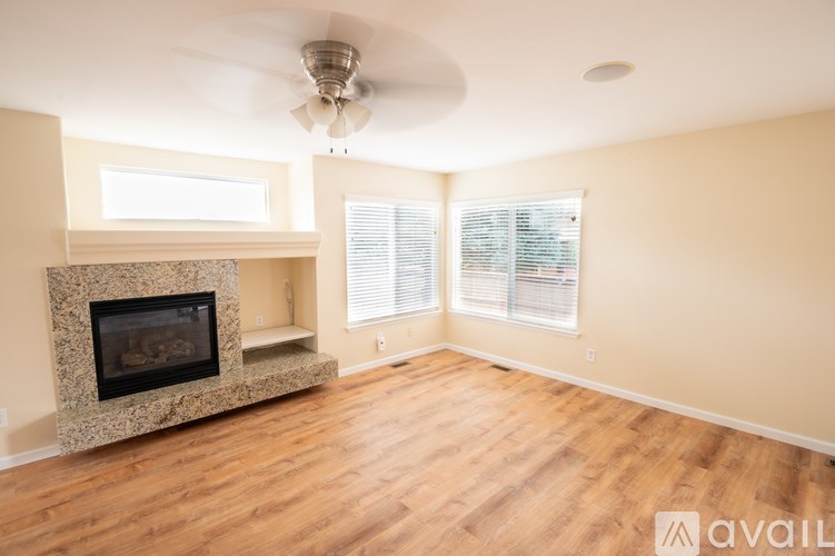 A living room with a fireplace and a fan on the ceiling.