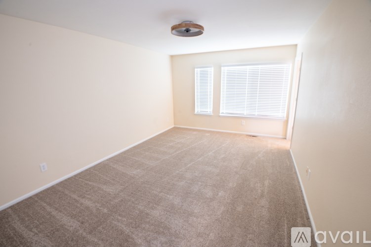 A room with a carpeted floor and a window with blinds.