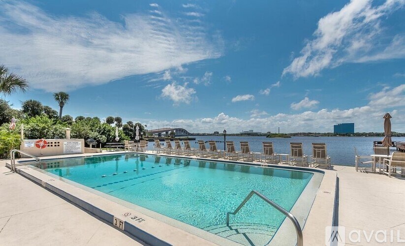 A large outdoor swimming pool with lounge chairs and a clear blue sky.