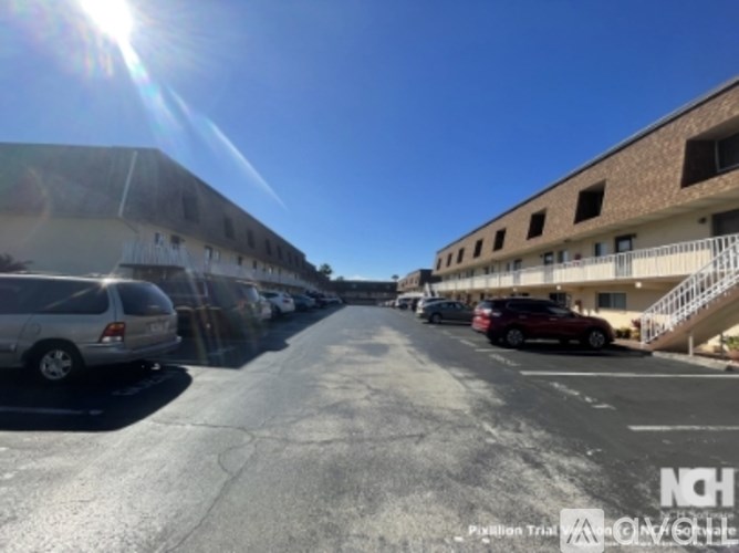 A sunny day at the parking lot of a building with cars parked.