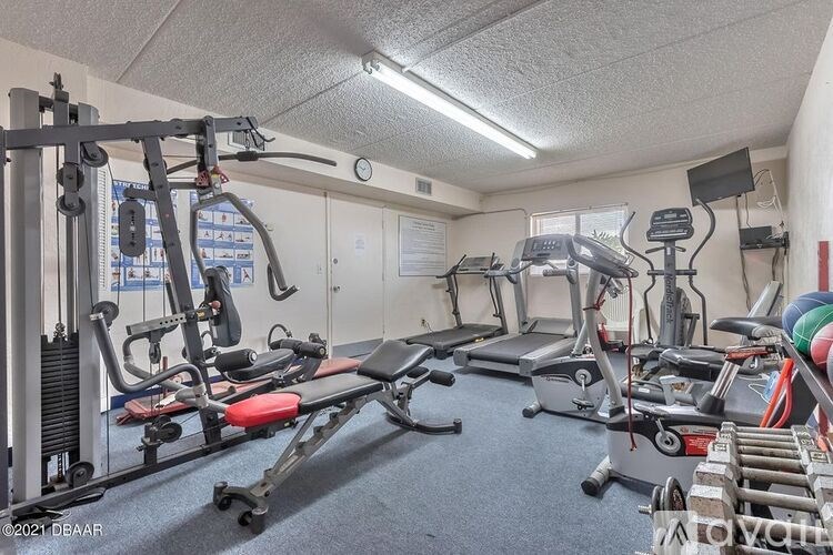 A gym with a variety of equipment including treadmills, weights, and exercise machines.