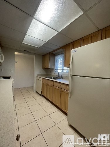 A kitchen with white appliances and wooden cabinets.