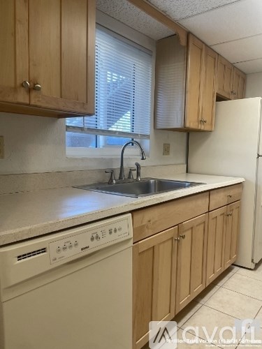 A kitchen with wooden cabinets and a white dishwasher.