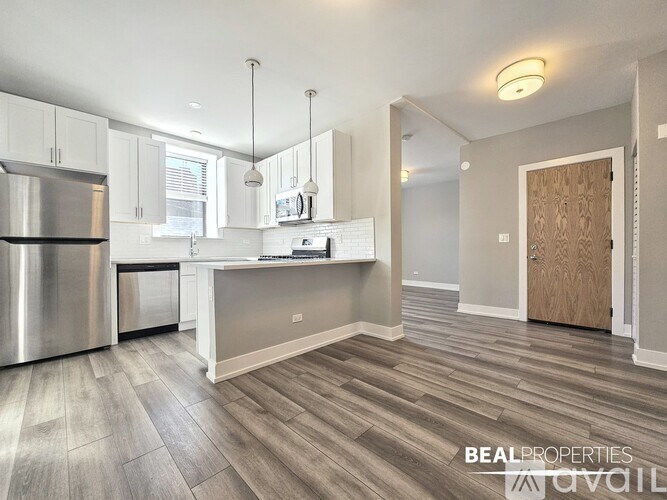 A modern kitchen with a stainless steel refrigerator and wooden flooring.