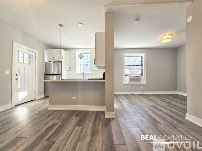 A spacious kitchen and living room with wooden flooring and white walls.