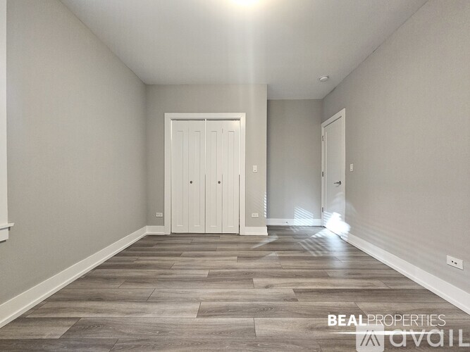 A spacious room with a wooden floor and a white door at the end.
