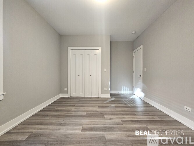 A spacious room with a wooden floor and a white door at the end.