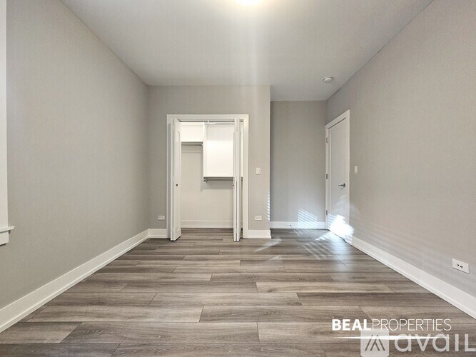 A spacious hallway with wood flooring and white walls.