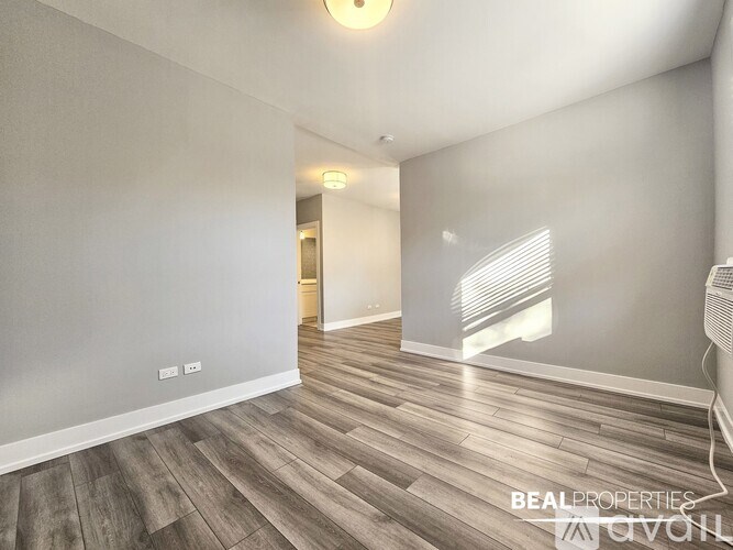 A spacious room with wooden flooring and white walls.