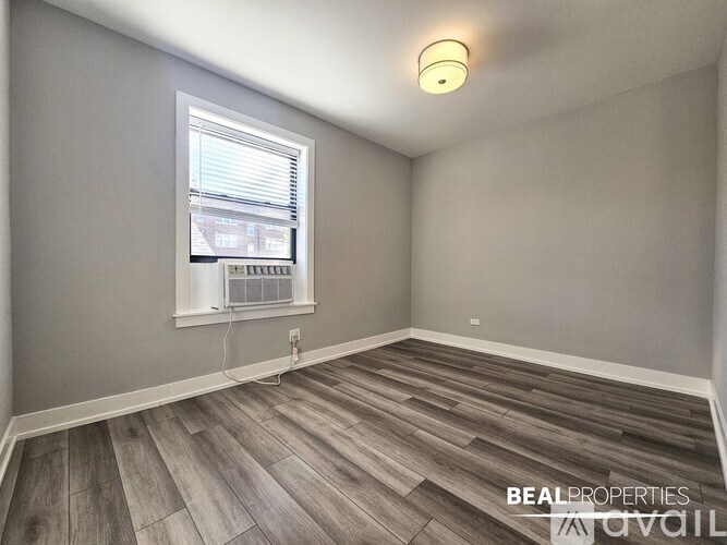 A room with wooden flooring and a window with blinds.