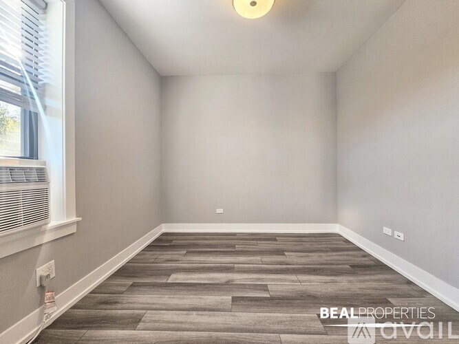A room with a window and a wooden floor.