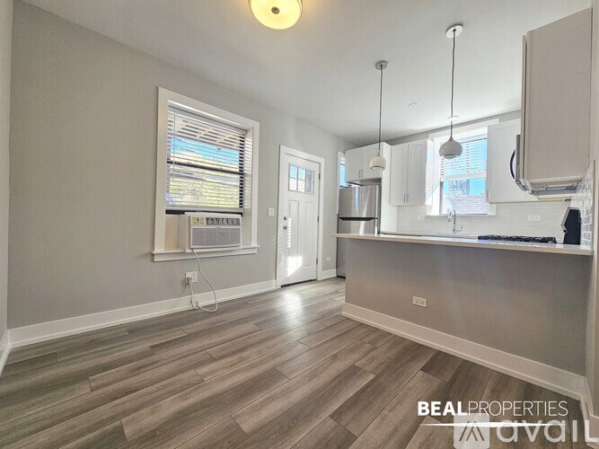 A kitchen with a wooden floor and a window with blinds.
