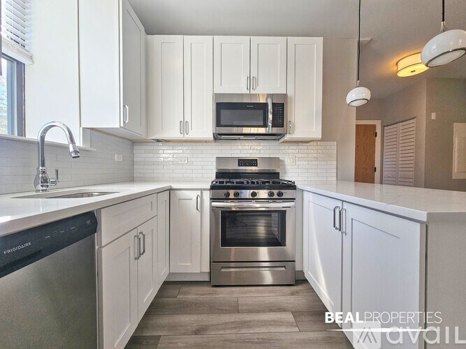 A modern kitchen with white cabinets and stainless steel appliances.