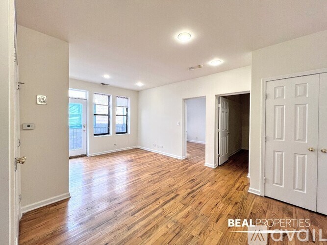 A spacious room with wooden flooring and white walls.
