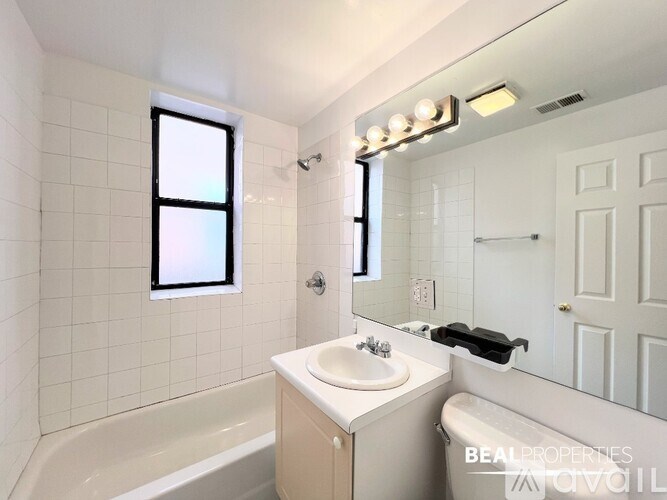 A white bathroom with a sink, mirror, and tub.