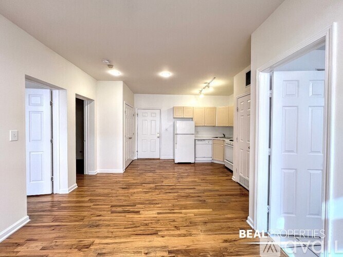 A spacious kitchen with white cabinets and a wooden floor.
