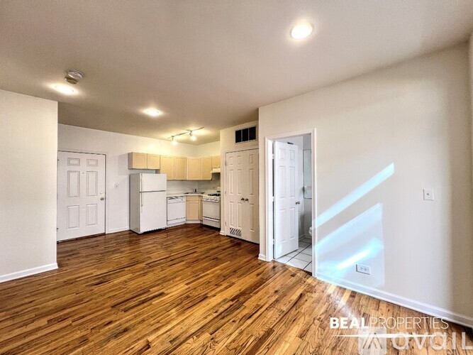 A spacious kitchen with white appliances and wooden floors.