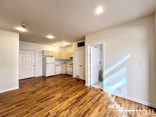 A spacious kitchen with white appliances and wooden floors.