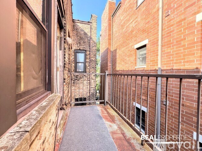 A narrow alleyway between two brick buildings with a metal railing on the right side.
