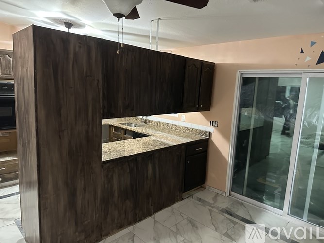 A kitchen with dark wood cabinets and a marble countertop.