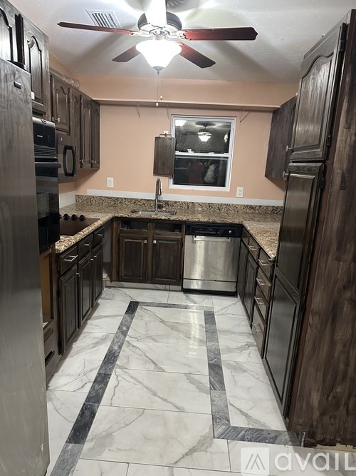 A kitchen with a marble floor and dark wood cabinets.