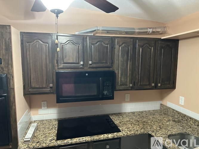 A kitchen with wooden cabinets and a black microwave.