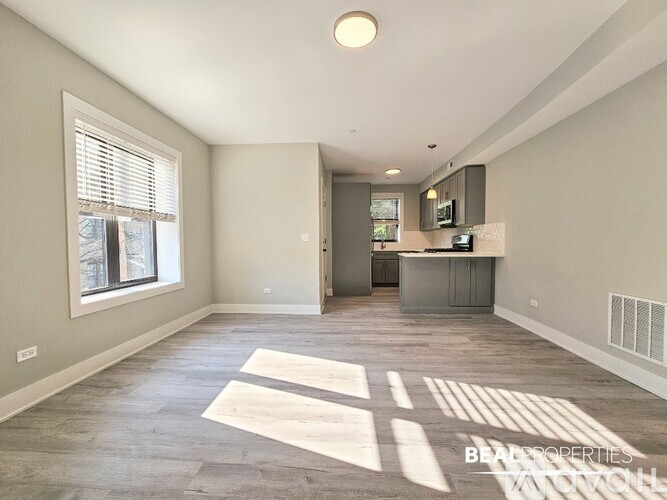 A spacious living room with a kitchen area in the background.