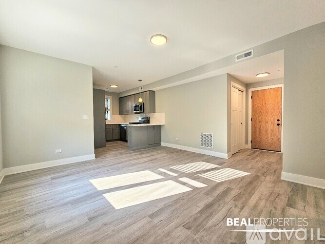 A spacious room with a kitchenette and a wooden door.
