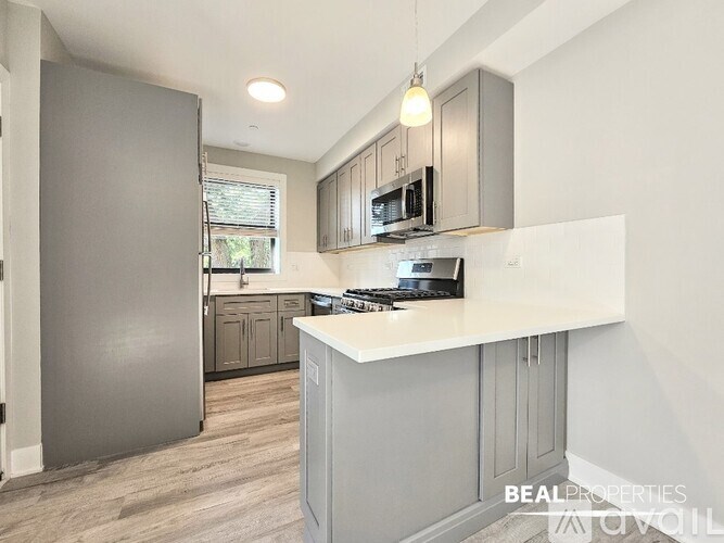 A kitchen with a refrigerator, microwave, and stove top oven.