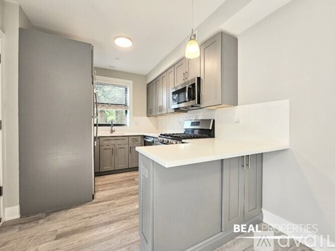 A kitchen with a refrigerator, microwave, and stove top oven.