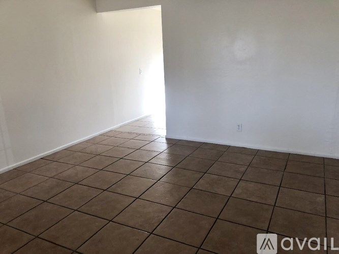 Empty room with brown tiled floor and white walls.