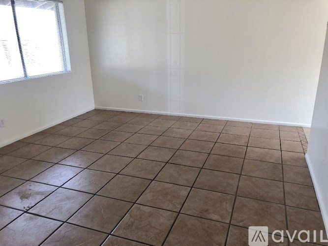 A room with brown tiled flooring and white walls.