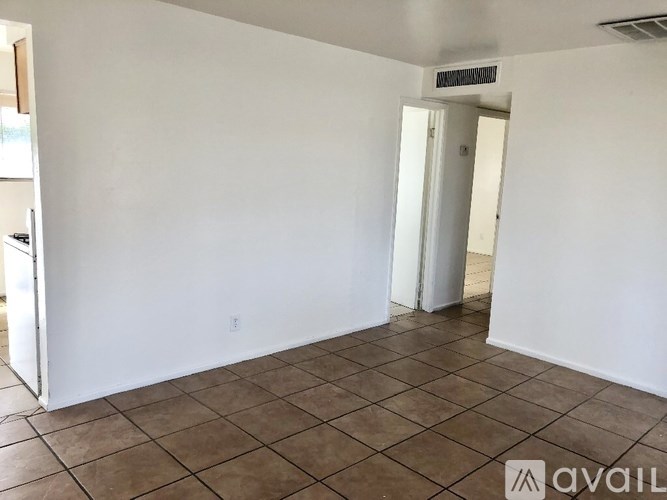 A room with white walls and brown tiled flooring.