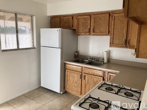 A kitchen with a white fridge, wooden cabinets, and a white stove top.